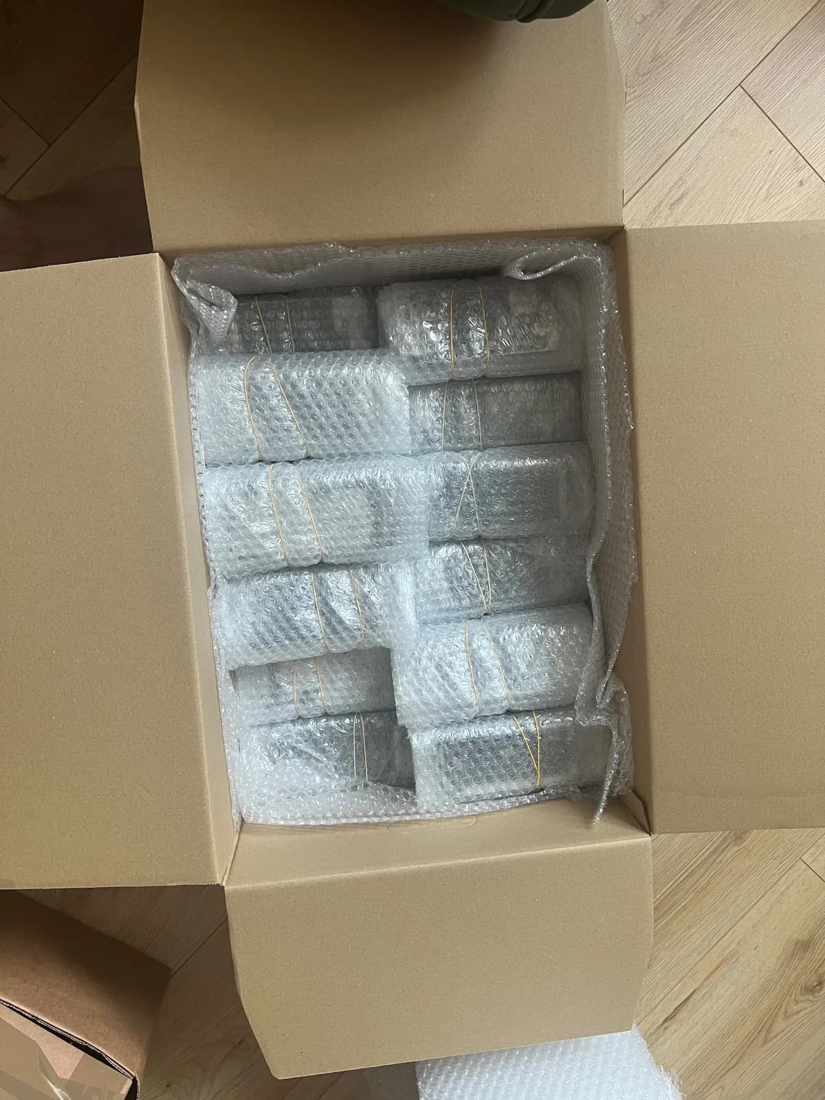 Bubble-wrapped screen bundles arranged inside an open cardboard box lined with cushioning.